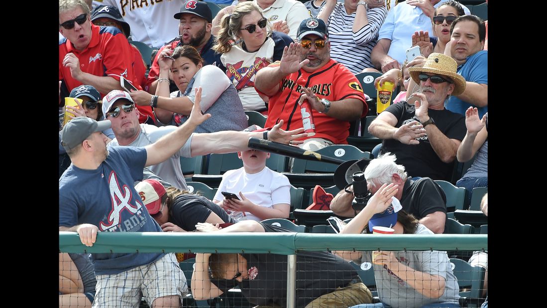 A man knocks down a baseball bat that flew into the stands during a spring-training game in Lake Buena Vista, Florida, on Saturday, March 5. The bat was heading toward a young boy who was looking at a cell phone.