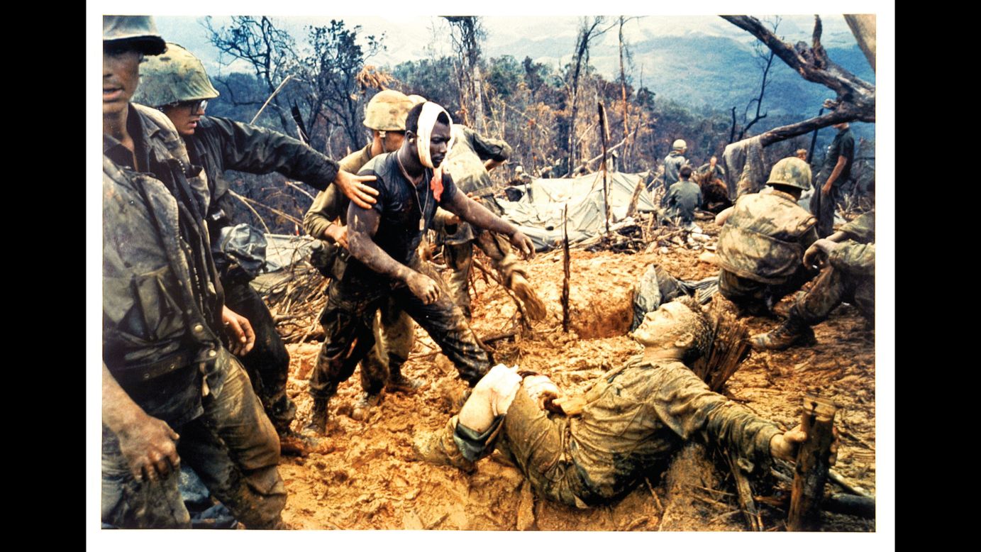 US Marine Gunnery Sgt. Jeremiah Purdie, with the bandaged head, reaches out to a wounded comrade during the Vietnam War in 1966. The photo was taken by Larry Burrows.