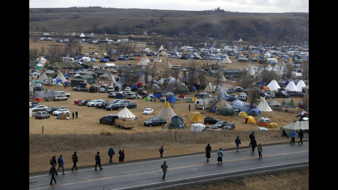 People protest along Highway 1806 as they walk past a sprawling encampment on Thursday, November 24.