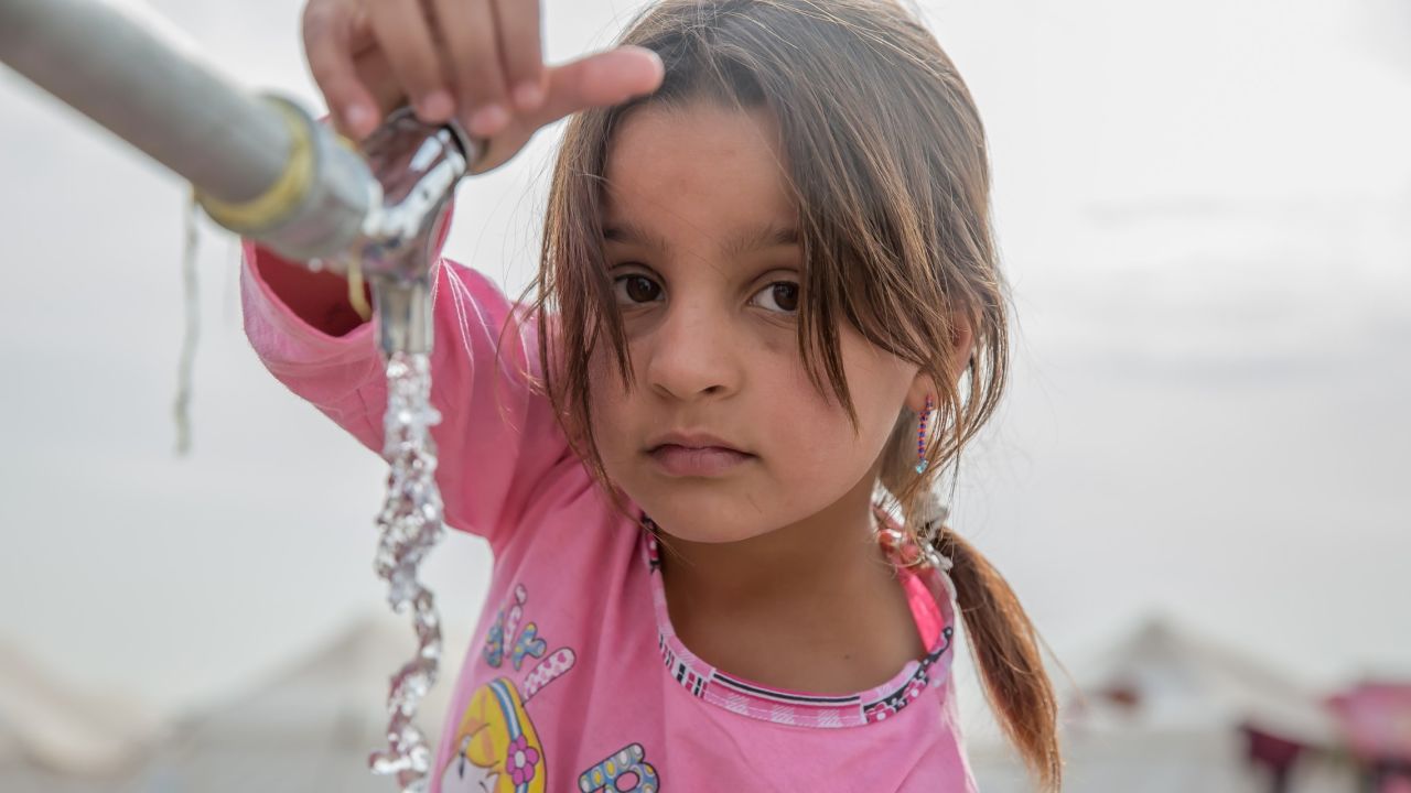 A young girl from Mosul gets water from a tap at a displacement camp in Iraq's Nineveh province.
