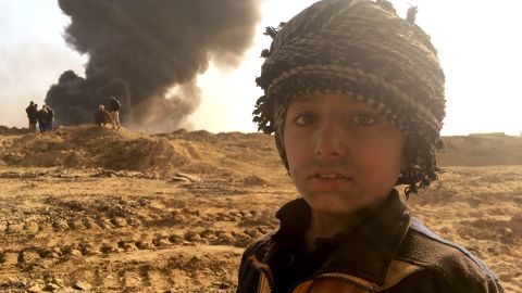 Families live beneath the towering columns of smoke and it is unclear how this toxic legacy left by ISIS will affect their health. 