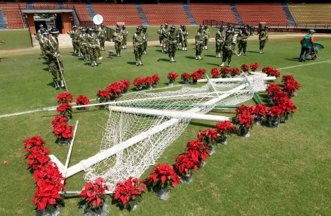 The posts of a soccer goal are decorated with flowers while members of a Colombian army band rehearse for the tribute in Medellin on November 30.