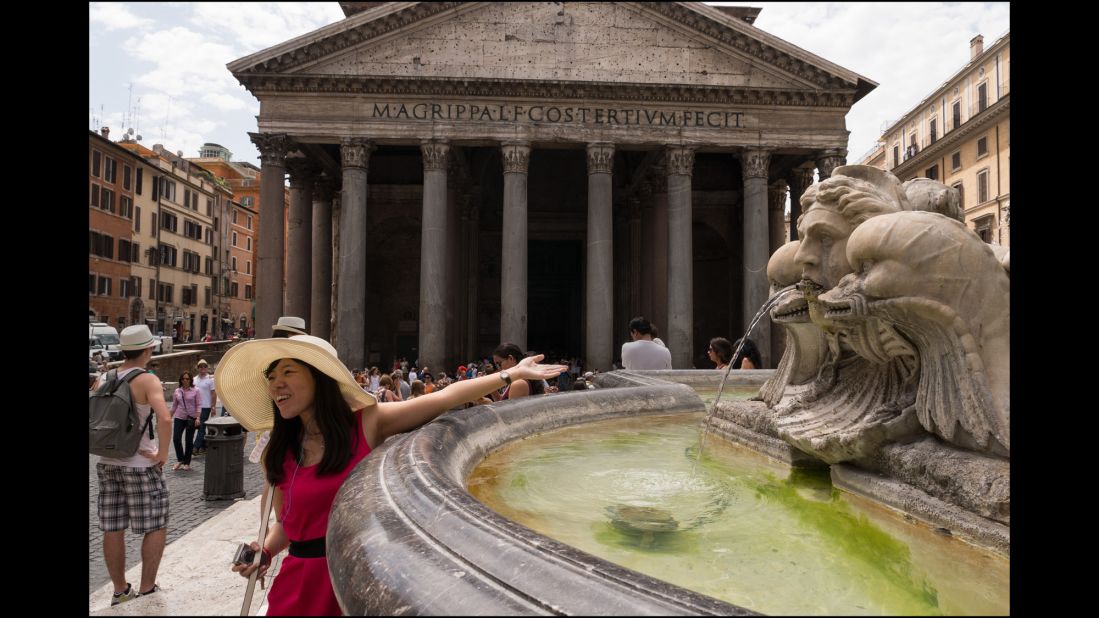 A young woman reaches over the fountain outside the Pantheon. The Fontana del Pantheon was commissioned by Pope Gregory XIII in 1575.