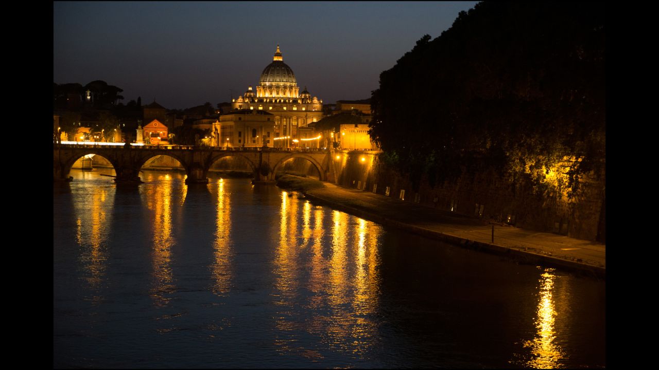A view along the Tiber of St Peter's Basilica and the Ponte de Sant' Angelo at night.