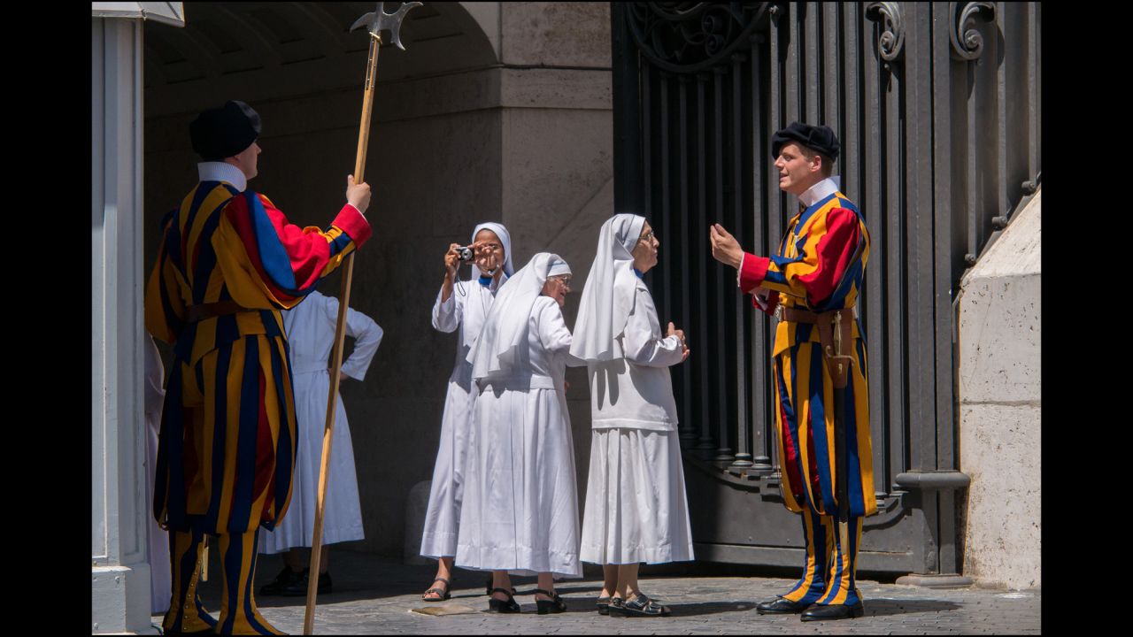A group of nuns at the entrance to the Vatican take pictures and ask questions of the Swiss Guard on duty.