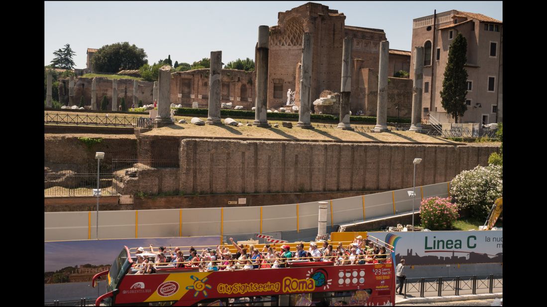 A tourist bus passes the ancient columns in front of the Chiesa di Santa Francesca Romana on the Roman Forum.