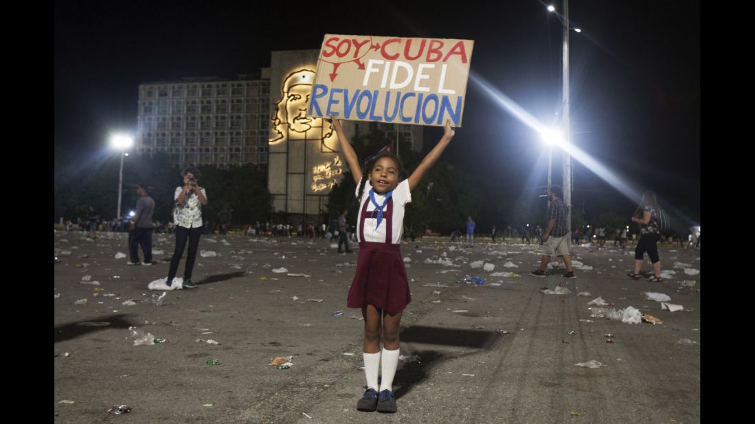 A girl in Havana holds a sign that reads "I am Cuba. I am Fidel. I am revolution" on Tuesday, November 29.