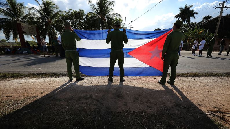 Ministry of Interior troops hold a Cuban flag as they wait for the military caravan transporting Castro's remains on November 30.