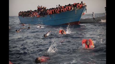 <strong>August 29:</strong> Migrants swim away from a crowded wooden boat as they are rescued in the Mediterranean Sea north of Sabratha, Libya. Thousands were rescued from more than 20 boats.