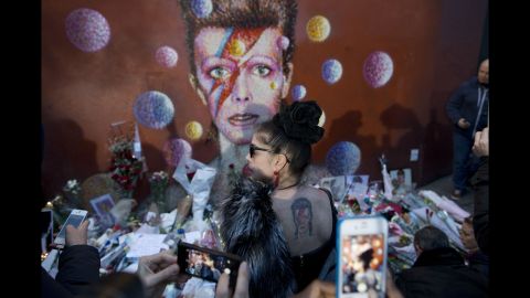 <strong>January 11:</strong> A woman with a David Bowie tattoo poses in front of a Bowie mural in London. The rock legend <a href="http://www.cnn.com/2016/01/11/entertainment/david-bowie-death/" target="_blank">died a day earlier</a> after an 18-month battle with cancer. He was 69.