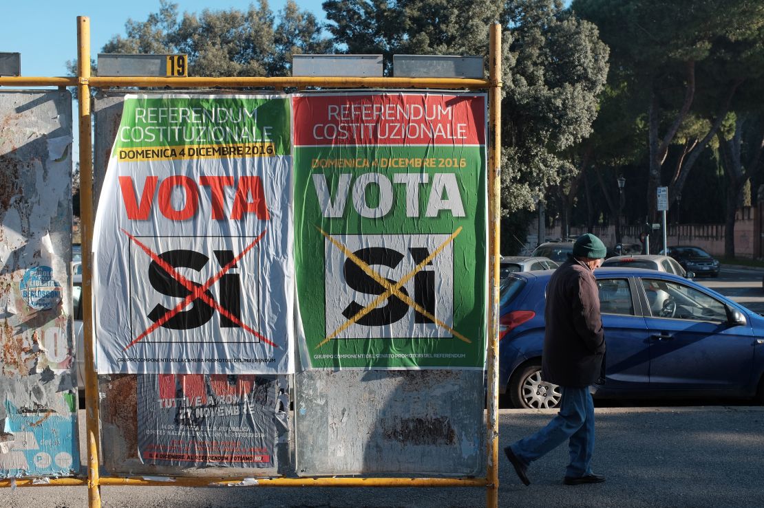 A man walks past posters calling for a "Yes" vote in Italy's constitutional referendum.