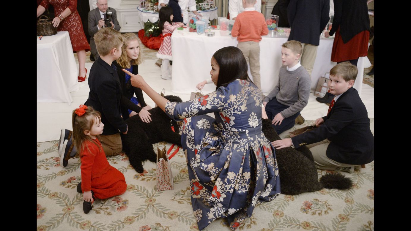 First Lady Michelle Obama, with the First Family's dogs Sunny and Bo, greets children of military families at the unveiling of the 2016 White House holiday decorations in the State Dining Room on November 29.
