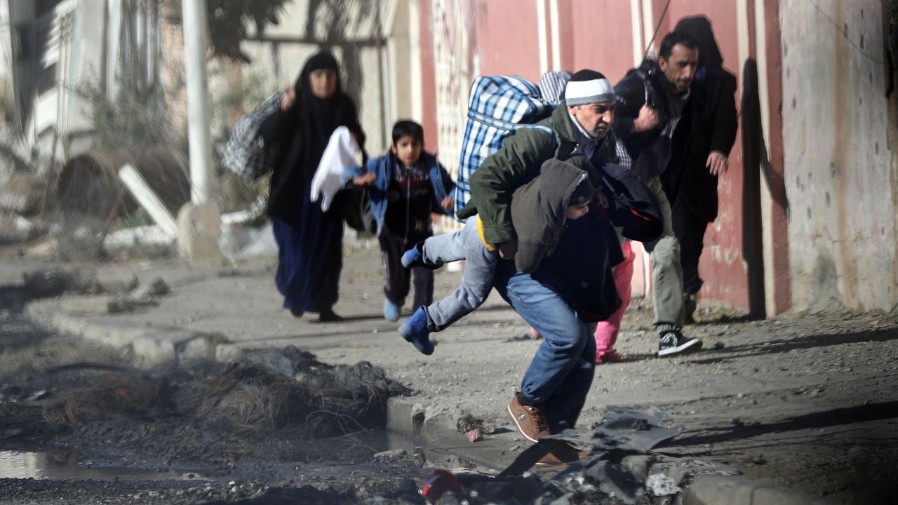 Iraqis run for cover as ISIS fighters clash with government forces in a northeastern district of Mosul.