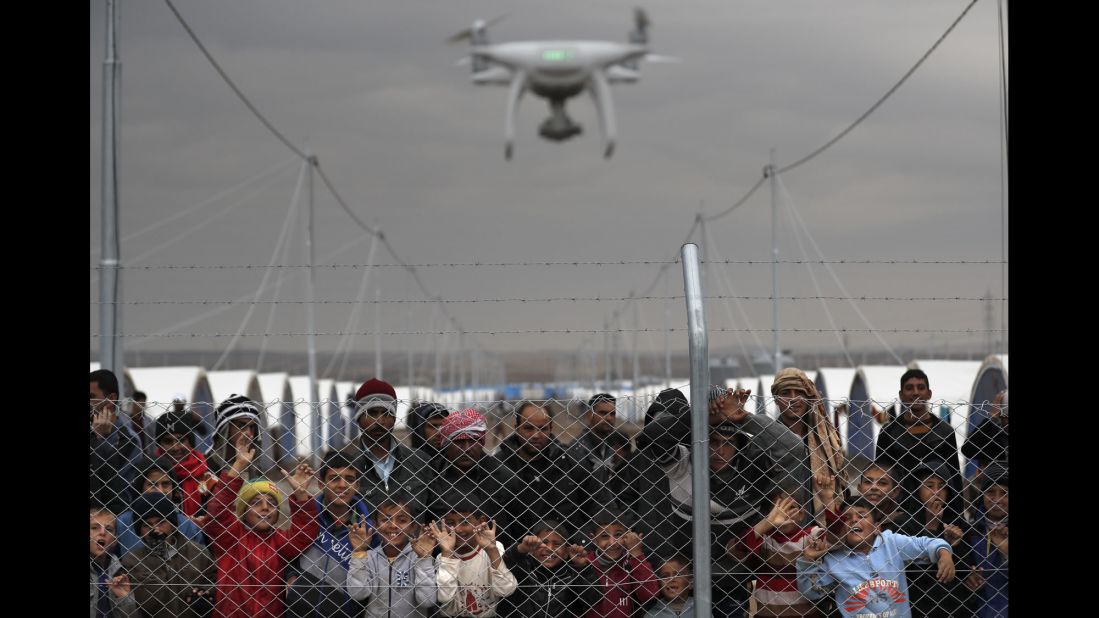Internally displaced Iraqis who fled the fighting in Mosul watch as a civilian drone films them at the al-Khazir camp on Thursday, December 1.