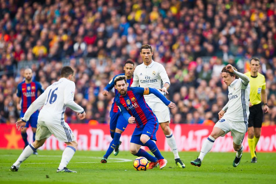 Lionel Messi is on the ball in El Clasico with his great rival Cristiano Ronaldo in the background.