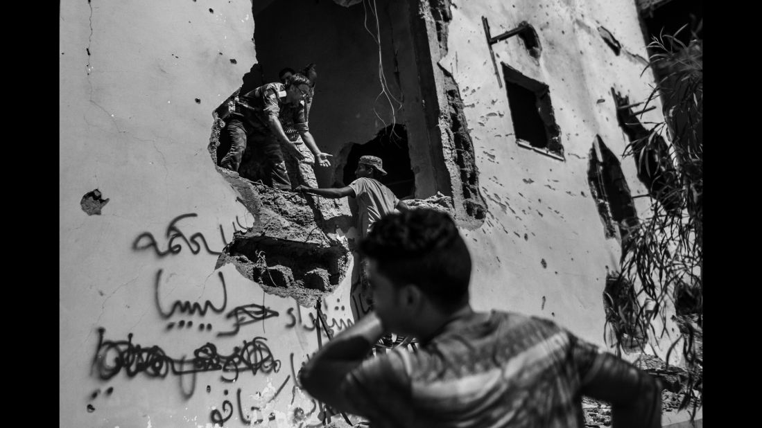 Libyan fighters enter a damaged building.