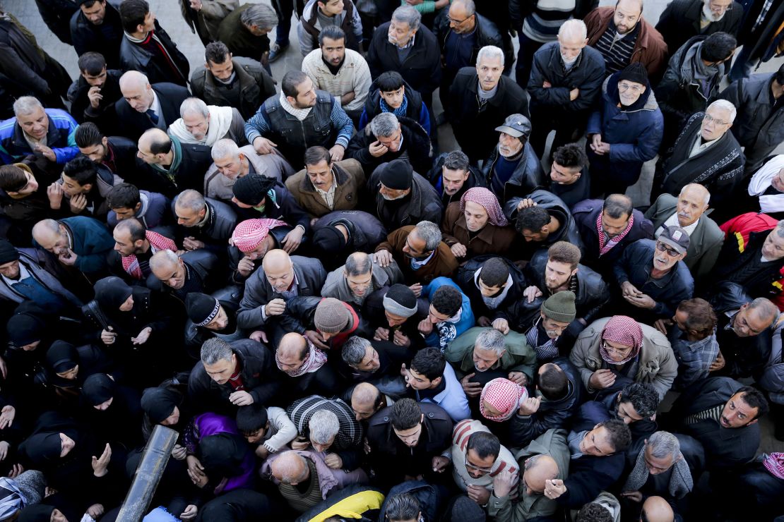 Syrian men wait for a security check to be able to return to their homes in Masaken Hanano in eastern Aleppo on Sunday. 