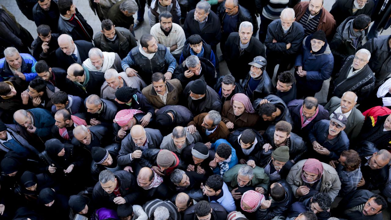 Syrian men wait for a security check to be able to return to their homes in Masaken Hanano in eastern Aleppo on Sunday.