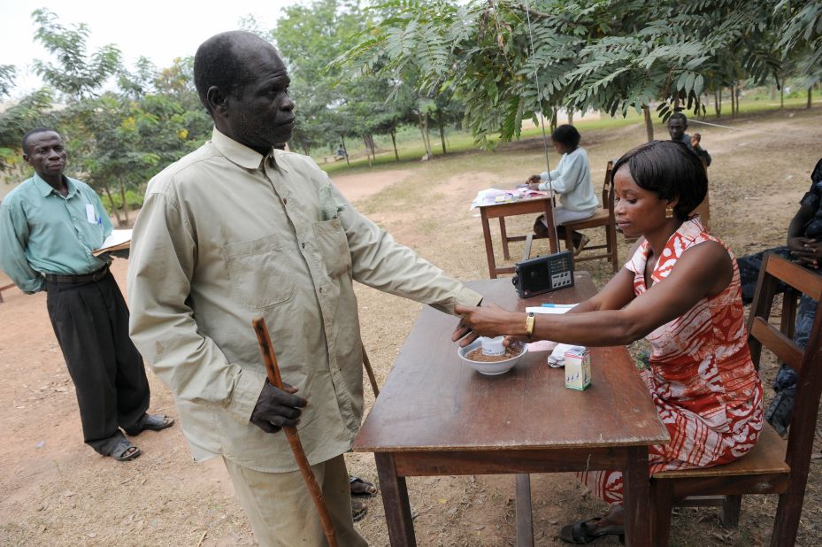 A sixty-year-old blind voter is helped by an electoral official to vote at Badu Central in Tain constituency.