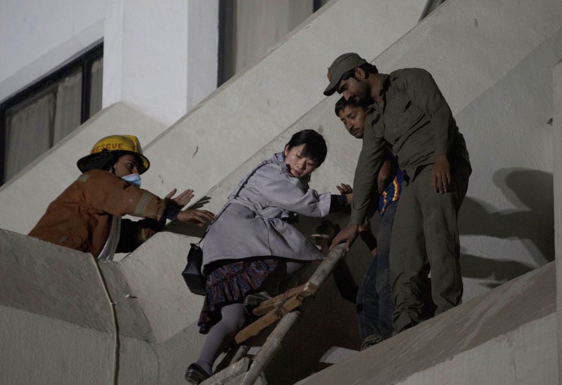 Pakistani volunteers help a foreigner to escape following a fire at a hotel in Karachi, Pakistan, Monday, December 5.