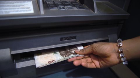 A customer withdraws Nigerian naira from an automated teller machine (ATM) at a bank in Asaba, Delta State.