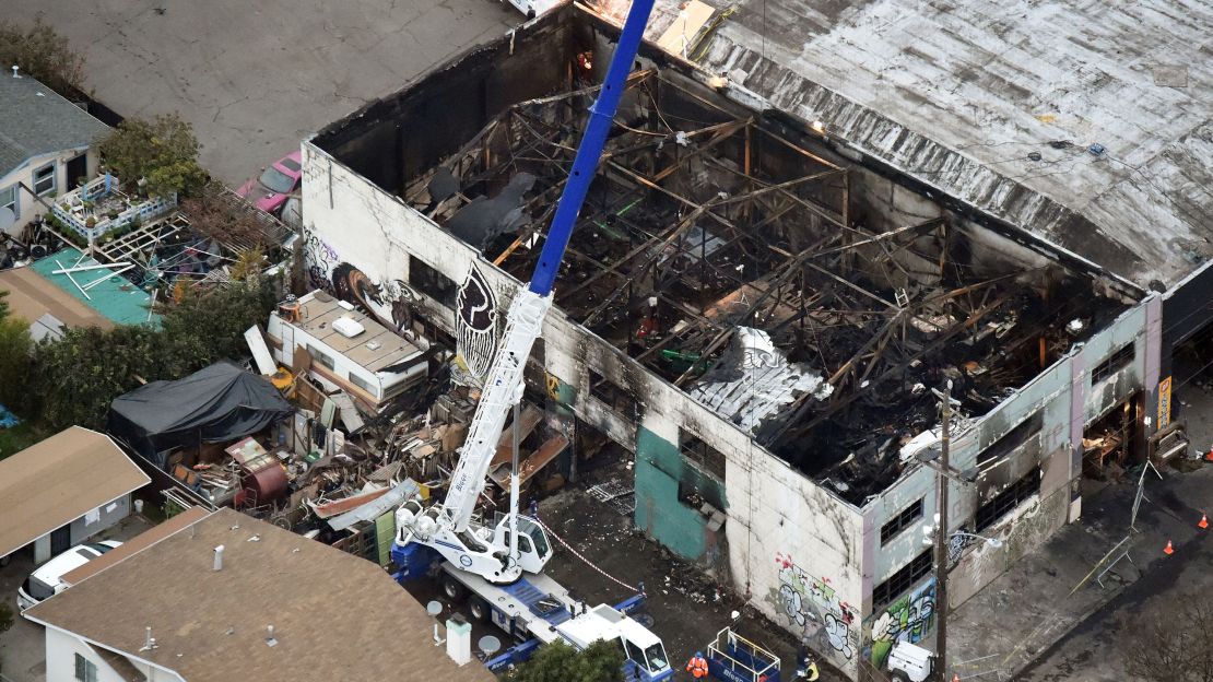 A crane lifts wreckage from the Oakland warehouse where at least 36 people died in a fire. 