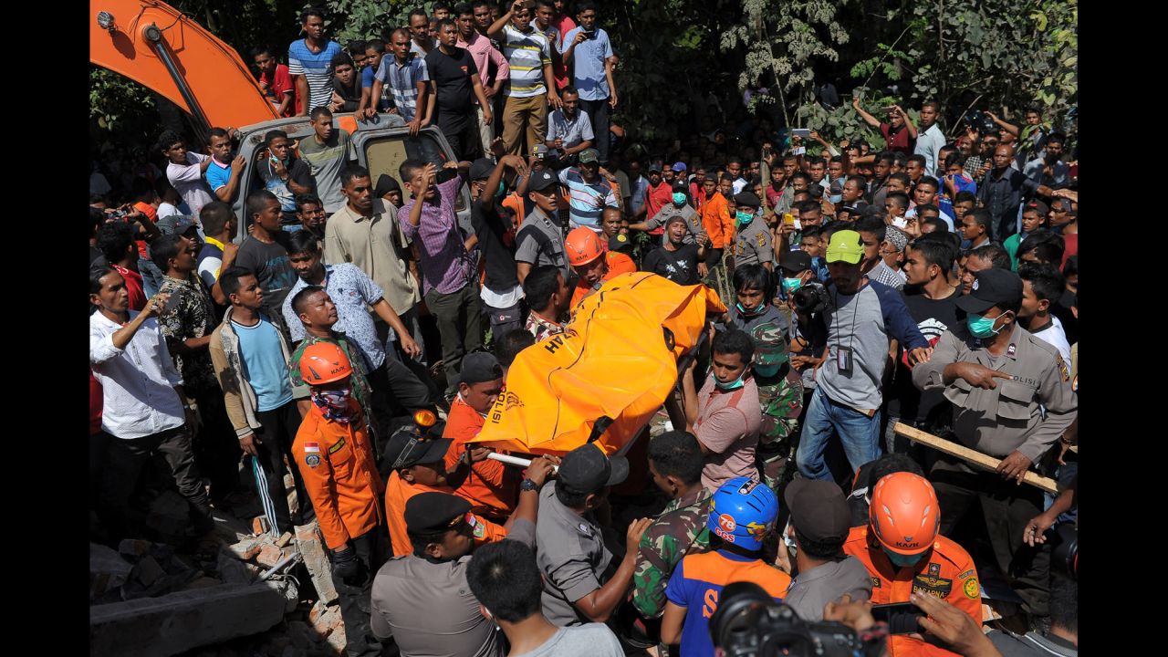 Rescuers carry the body of an earthquake victim in Pidie Jaya.