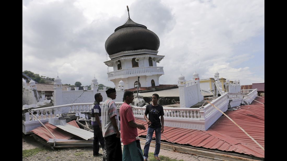 Men inspect a mosque that collapsed during the quake, which struck just as people were preparing for morning prayers on December 7. 