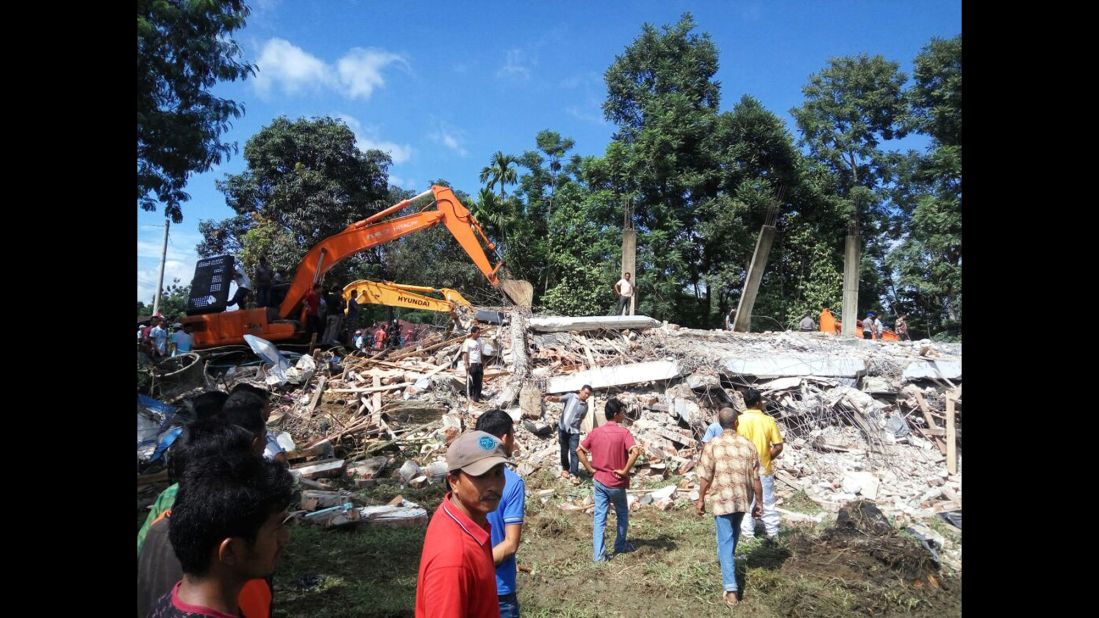 Rescuers use heavy machinery to search for potential survivors under the rubble of a collapsed building in Pidie Jaya.