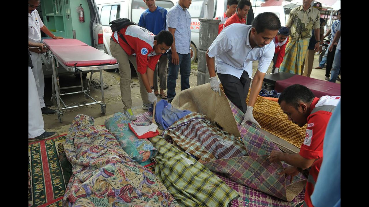 Indonesian Red Cross volunteers cover the bodies of victims at a hospital morgue. Additional medical workers had to be flown in after a local hospital was damaged in the quake.