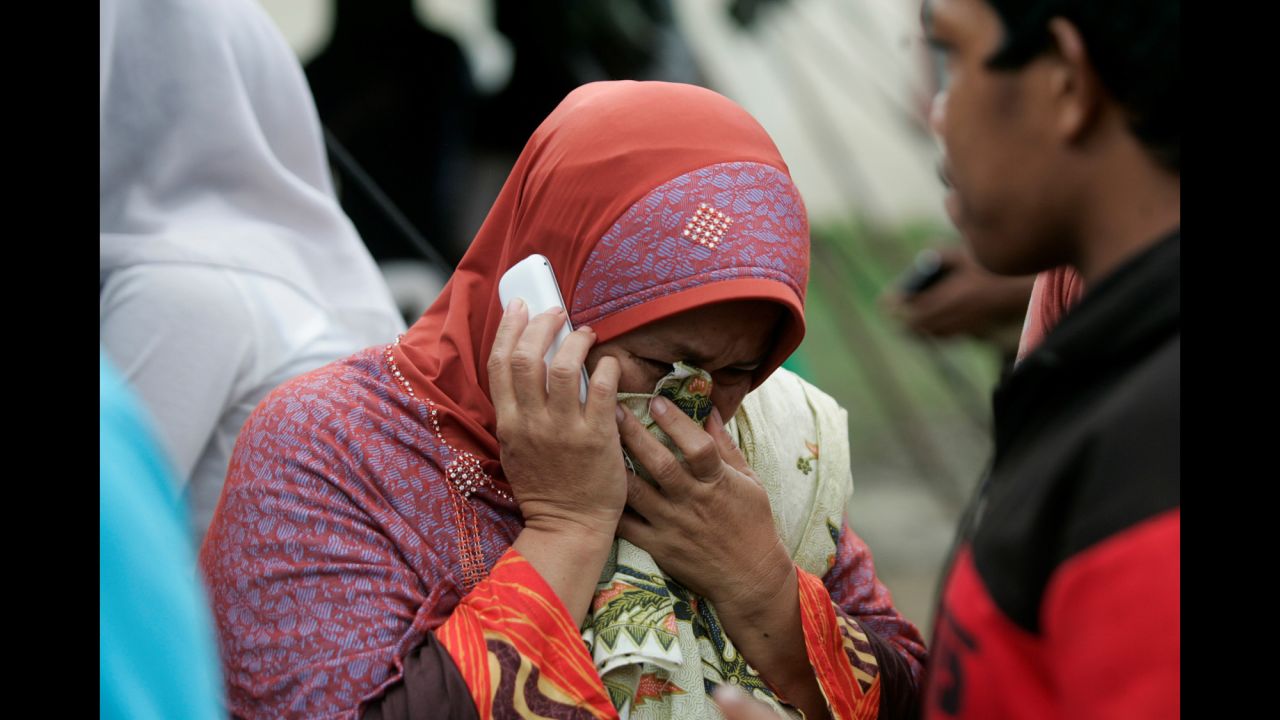 A distraught woman makes a phone call outside a hospital in Pidie Jaya.