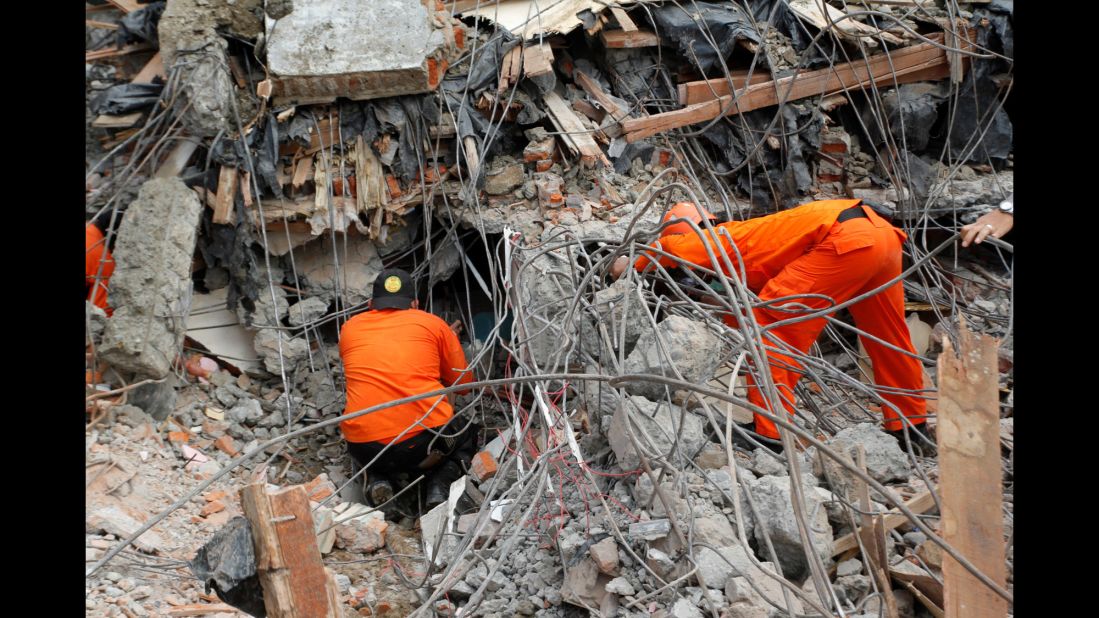 Emergency responders search through destroyed structures for survivors.