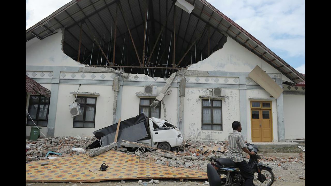 A man rides past a hospital that was heavily damaged by the  quake in Pidie Jaya.