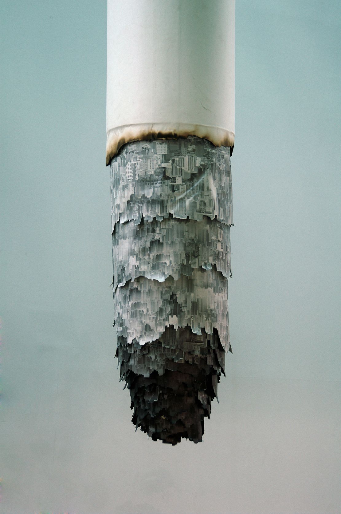 For this installation, Yang printed cityscapes on canvas and hung them from a PVC tube to resemble a large cigarette