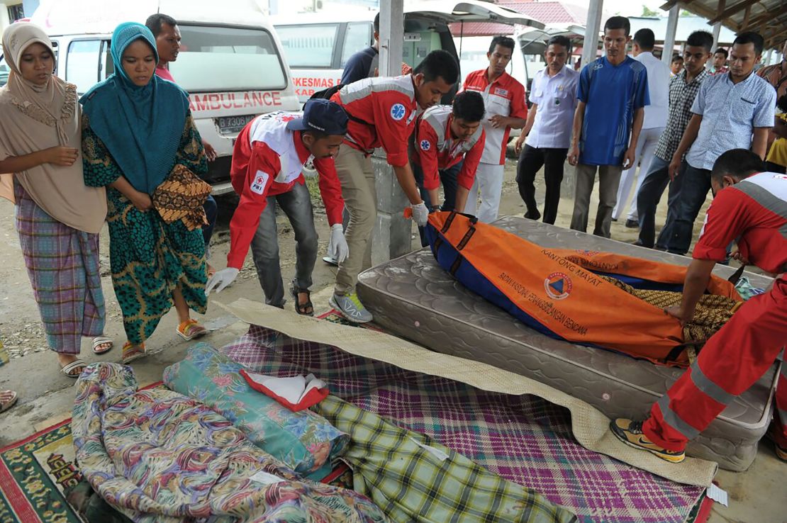 Women stand next to relatives who were killed in Wednesday's earthquake.