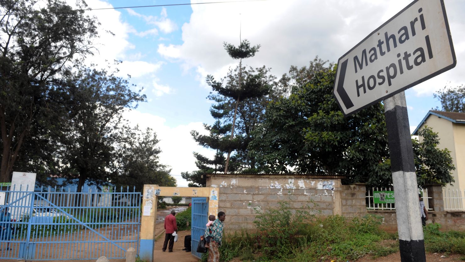 A woman carrying a baby walks past a sign showing the direction to the Mathari hospital on May 13, 2013 in Nairobi. 
