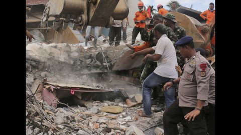 Rescuers work to recover the body of an earthquake victim from a collapsed building. The death toll is expected to rise as rescuers retrieve more victims from under the rubble.