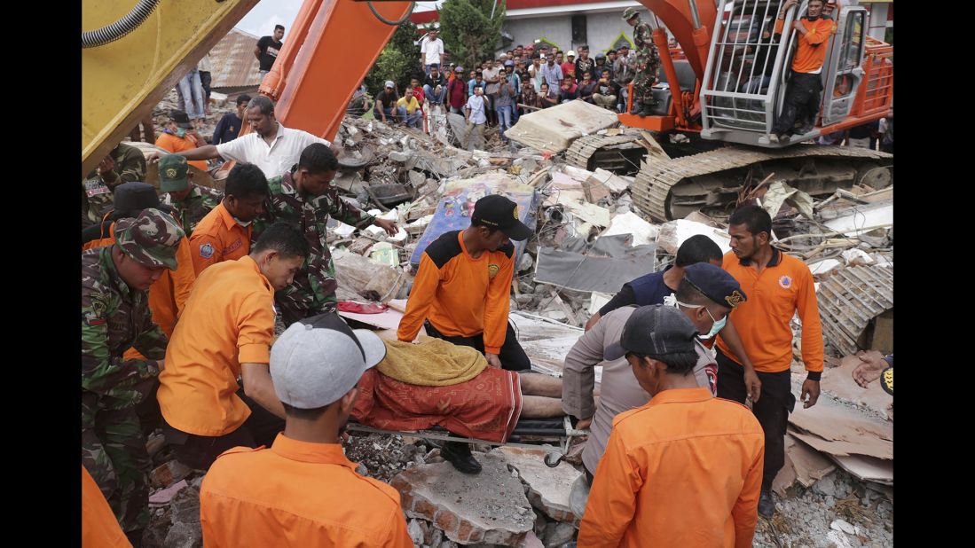 Rescuers recover a body from the rubble of a collapsed building in Pidie Jaya.