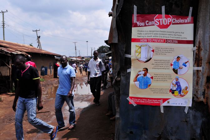 A further 76% of Kenyans believe that when children today in Kenya grow up, health care will be better.<br /><br />Pictured here, people walk past a kiosk where a poster on how to prevent Cholera is displayed in the Kibera area of Nairobi in May 2015. 
