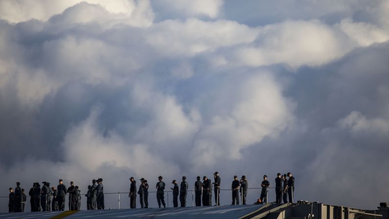 Crew members of the USS John C. Stennis stand on deck of the guided missile destroyer USS Halsey in Honolulu.
