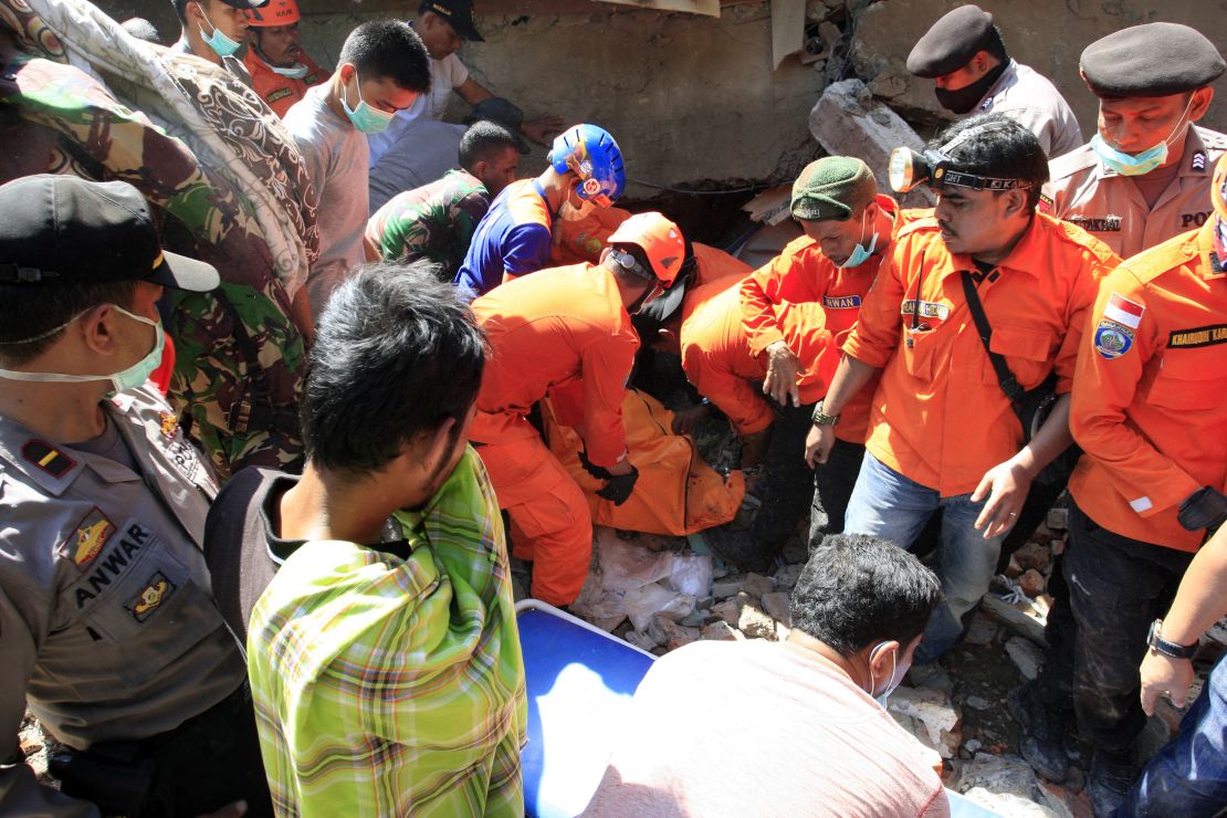 Rescue workers pull victims from destroyed buildings Wednesday in the town of Sigli.