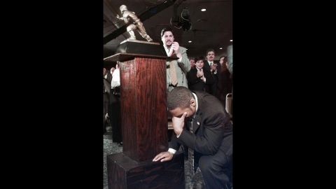 Michigan's Charles Woodson kneels beside the Heisman Trophy after becoming the first primarily defensive player to win the honor at the Downtown Athletic Club in New York on December 13, 1997.