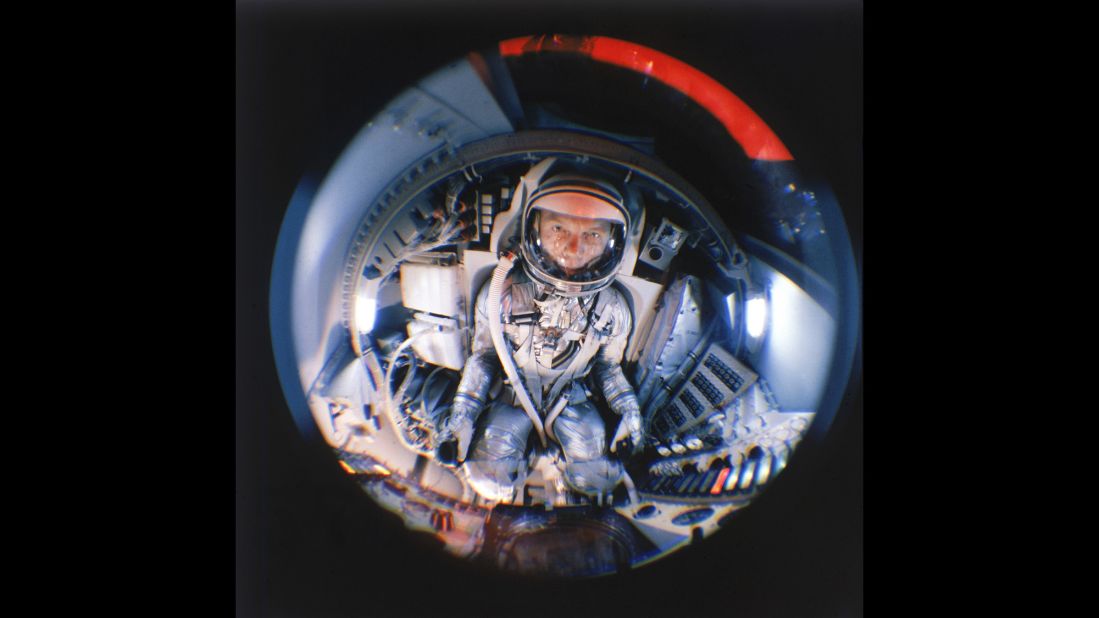 Glenn, now a Project Mercury astronaut, is seen through fisheye lens during training in a mock-up of a space capsule.