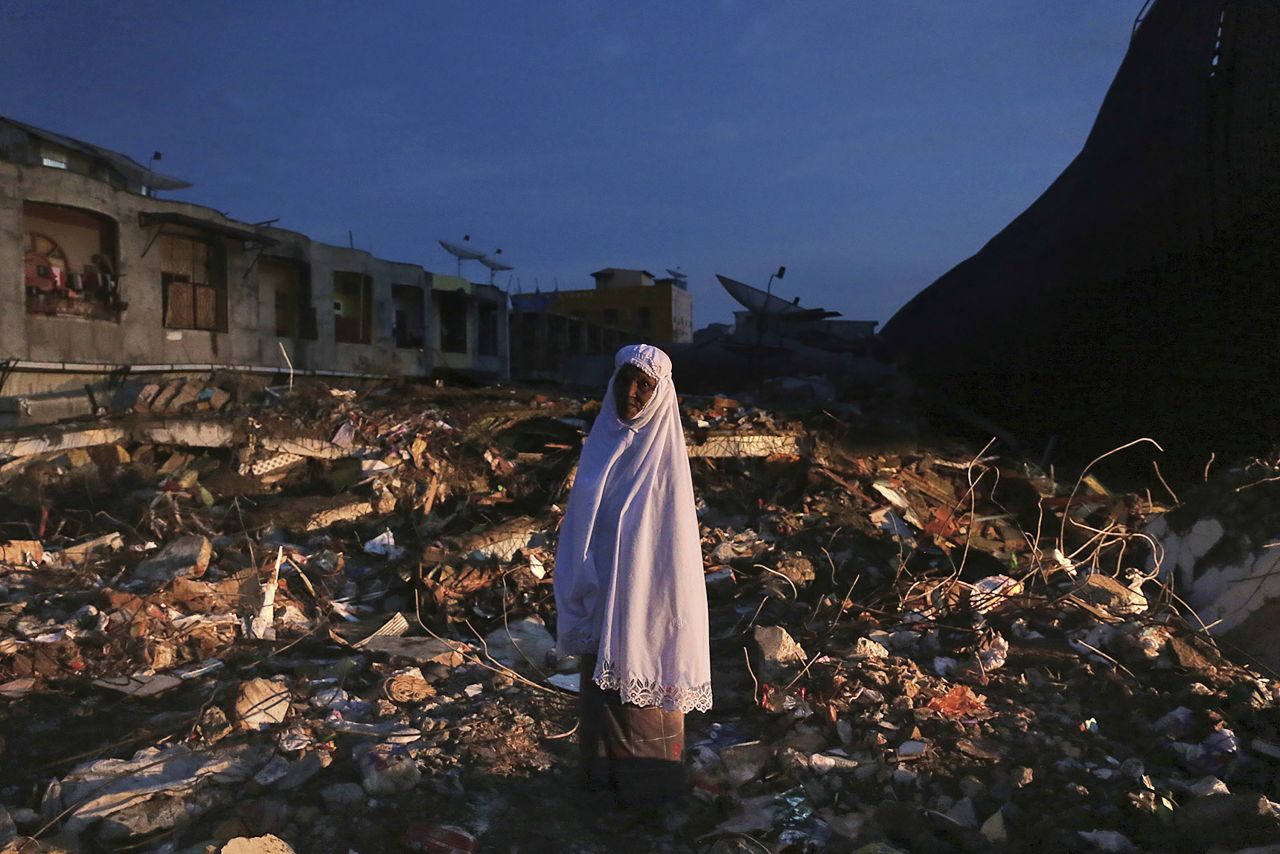 A woman stands amid the rubble of a market that was destroyed in the quake in Meureudu, on December 8.