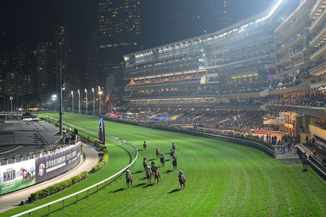 Competitors round the bend under the floodlights, with Hong Kong's skyline in the background.