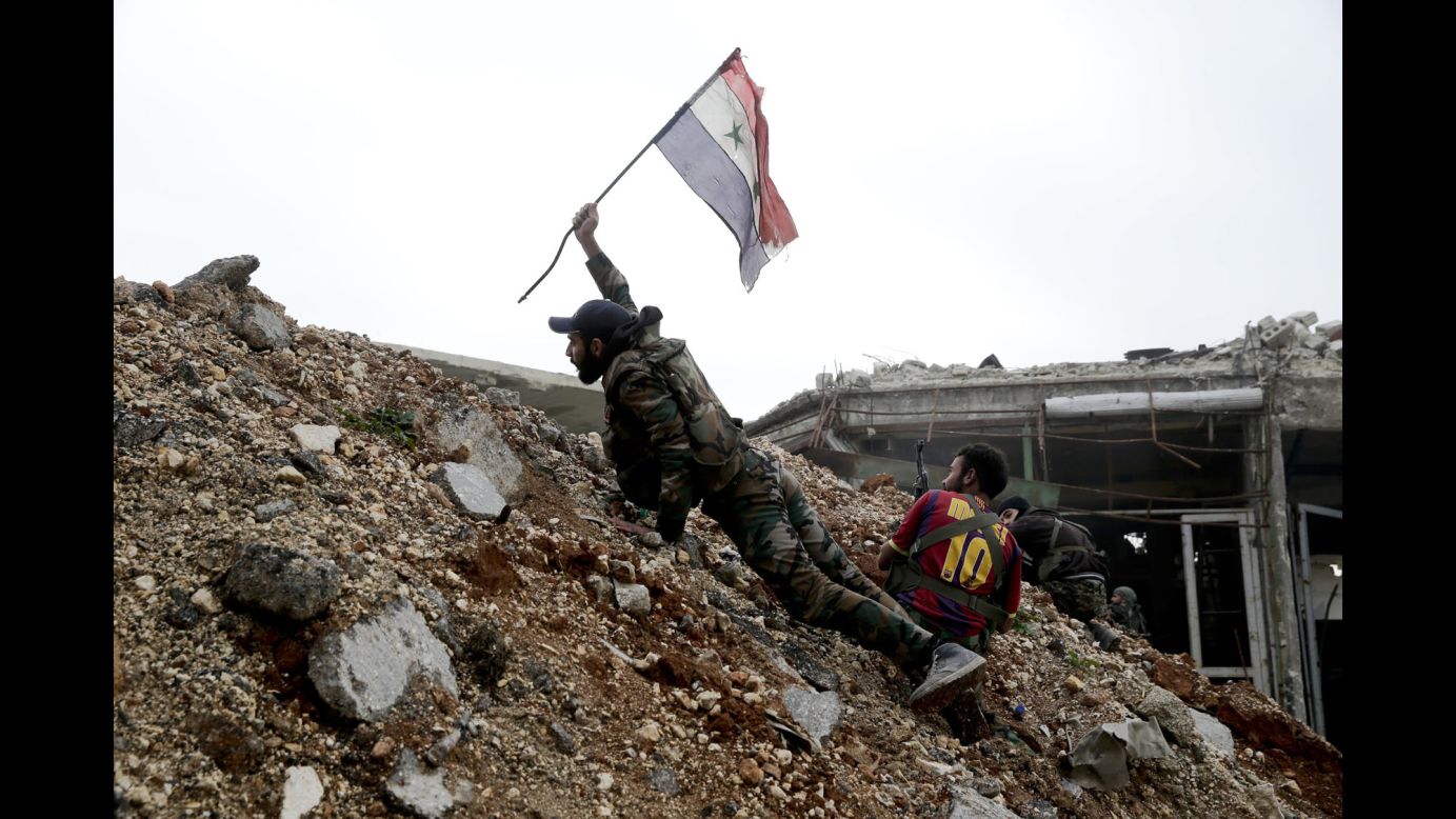 A Syrian Army soldier places a Syrian flag in the ground during a battle with rebel fighters in Aleppo, Syria, on Monday, December 5.