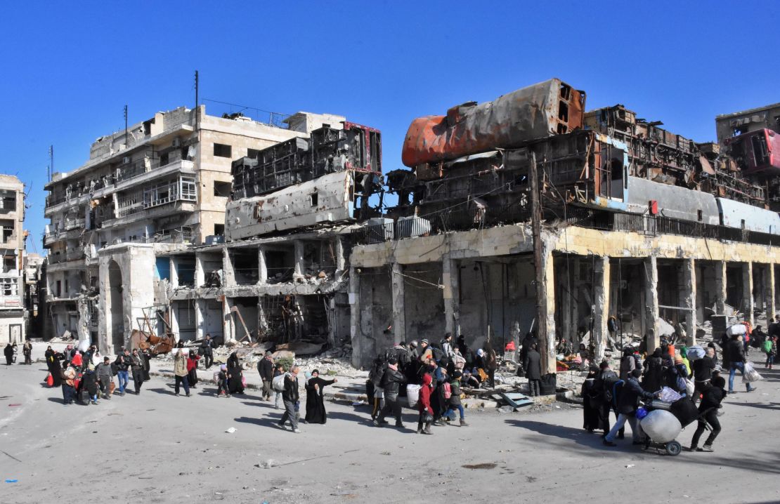 Residents of a newly retaken eastern neighbourhood of Aleppo pass a makeshift barricade Thursday.