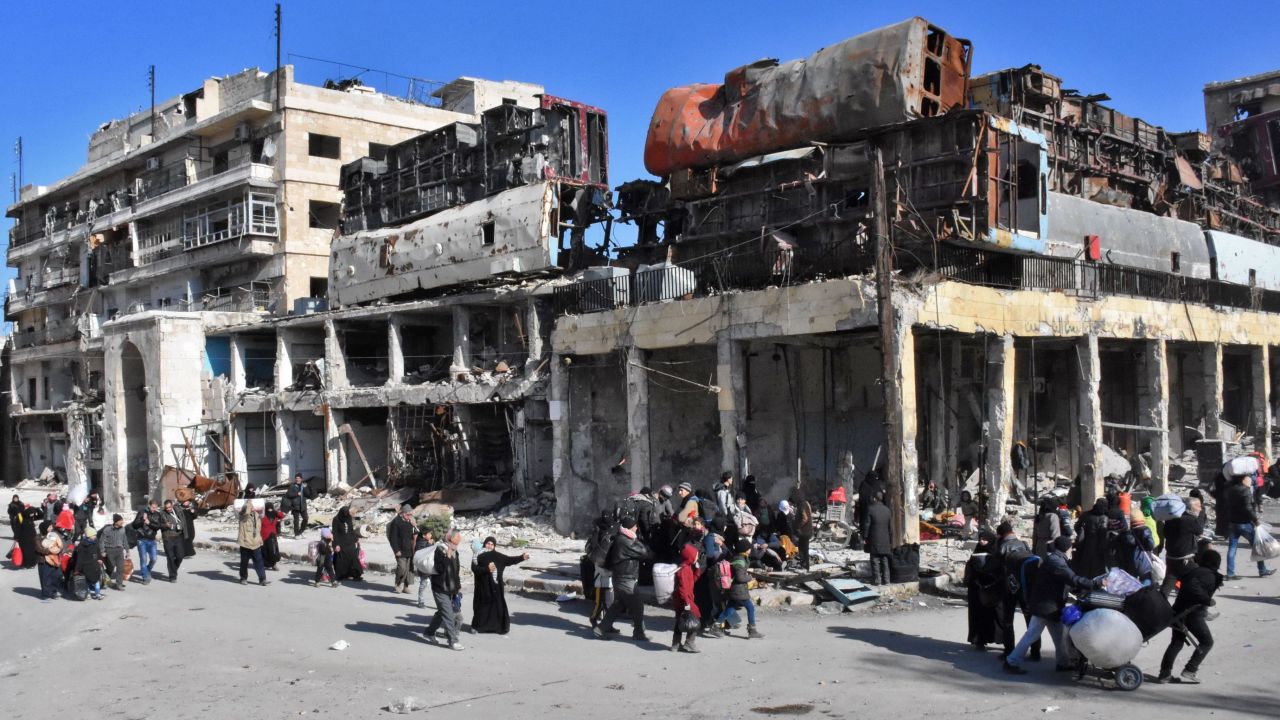 Residents of a newly retaken eastern neighbourhood of Aleppo pass a makeshift barricade Thursday.