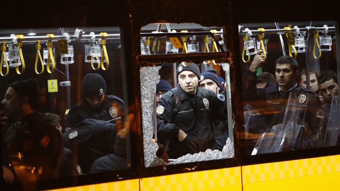 Police officers stand inside a damaged bus after an explosion.