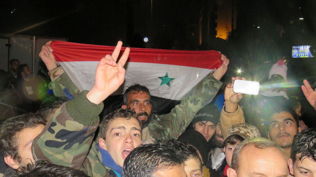 Syrians celebrate in a government-held district of Aleppo on Monday, December 12.